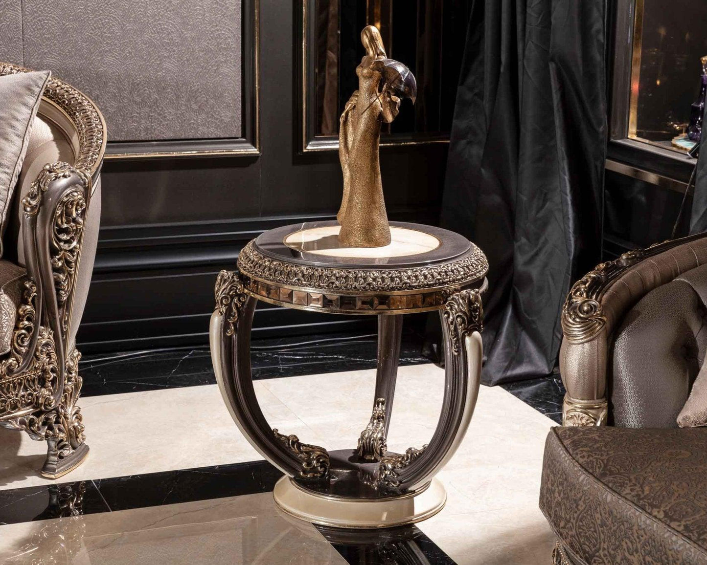 A luxurious French design side table with a carved mahogany wood top and base, featuring a silver-colored metal leg, placed in an elegant room setting with a decorative lamp on top.