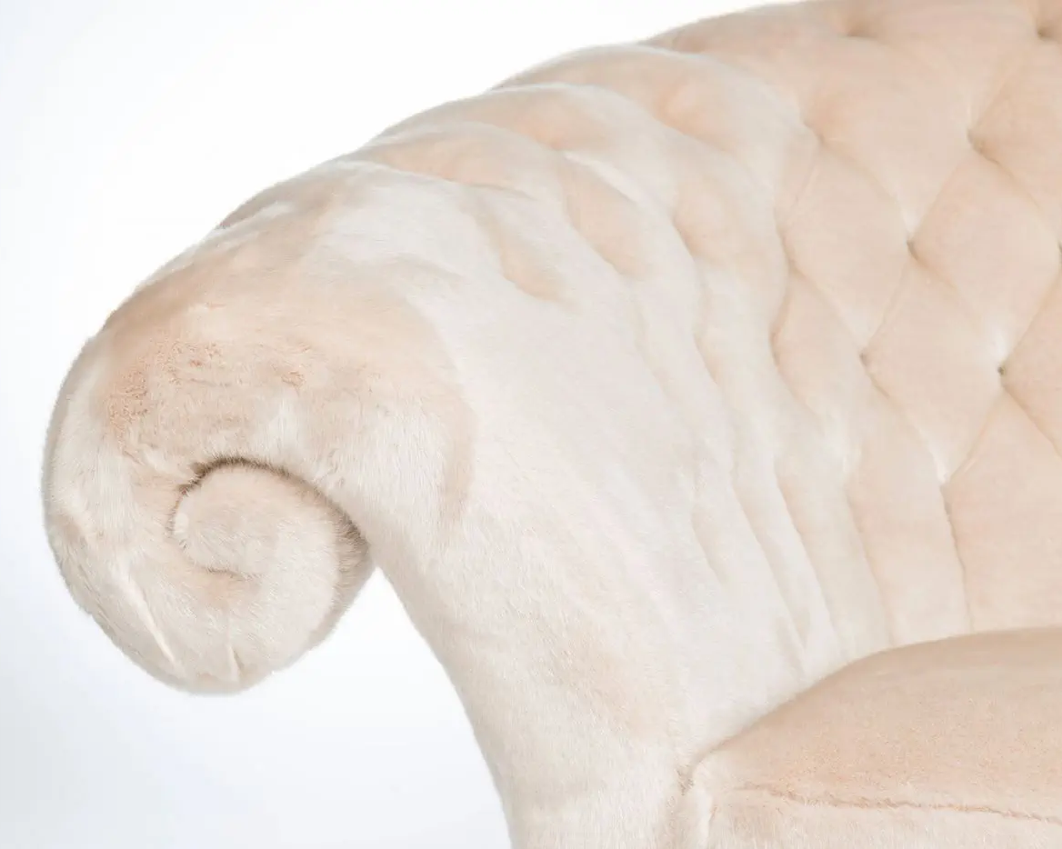 Close-up of a plush, beige armchair with a tufted backrest on a white background