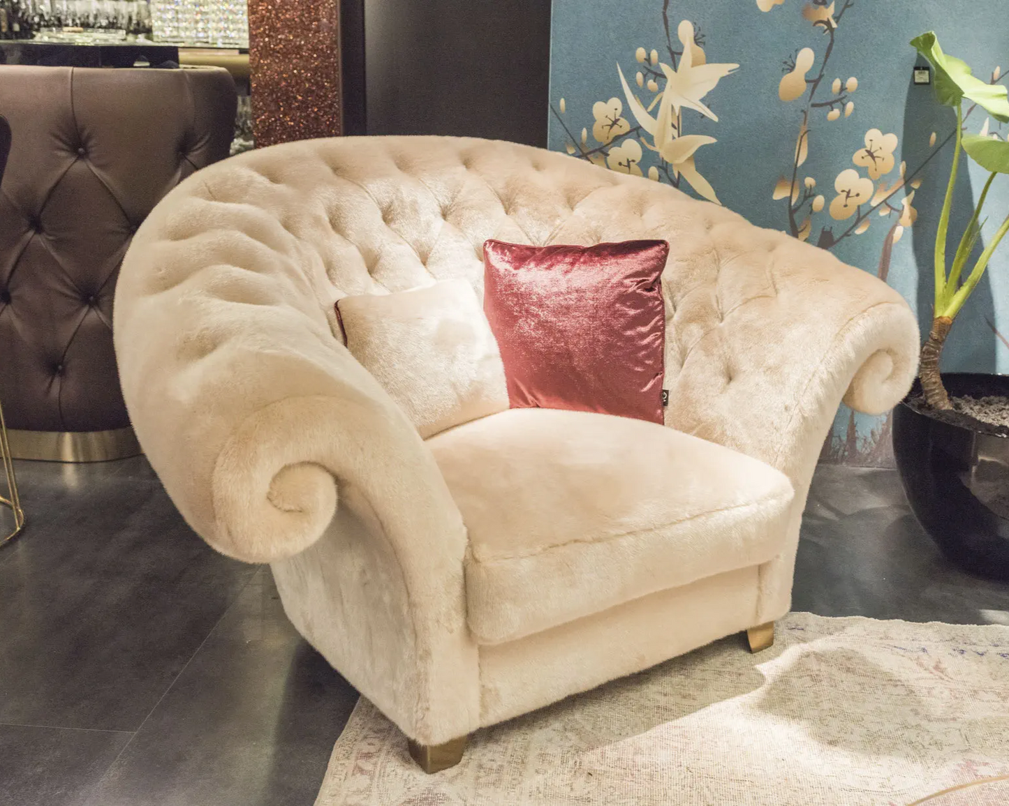 Beige armchair with a red pillow in a room setting with decorative elements.
