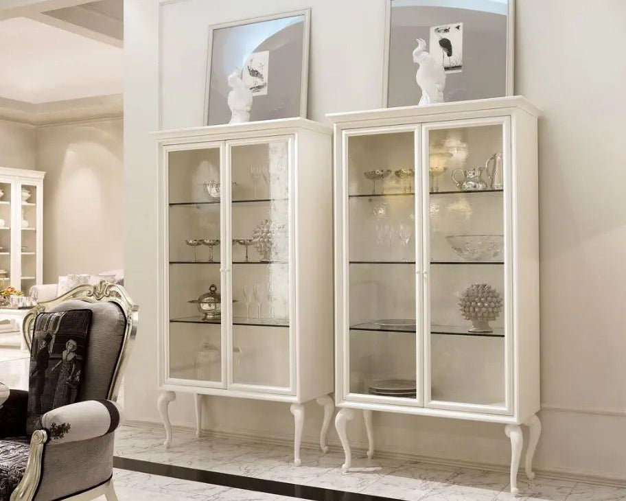 White glass-fronted cabinet in a room with decorative items on shelves.