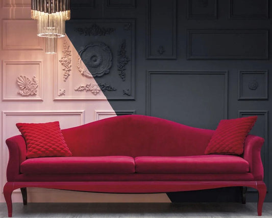 Red sofa with decorative pillows in a room with ornate wall designs and a chandelier.