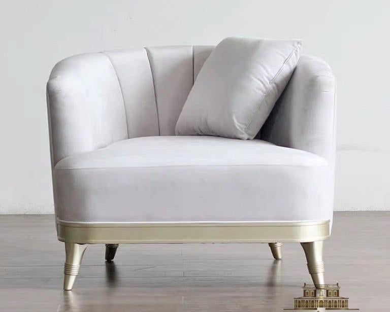 A modern 'light luxury' style armchair with gold elements and a gray upholstery, standing on a wooden frame with metal legs.