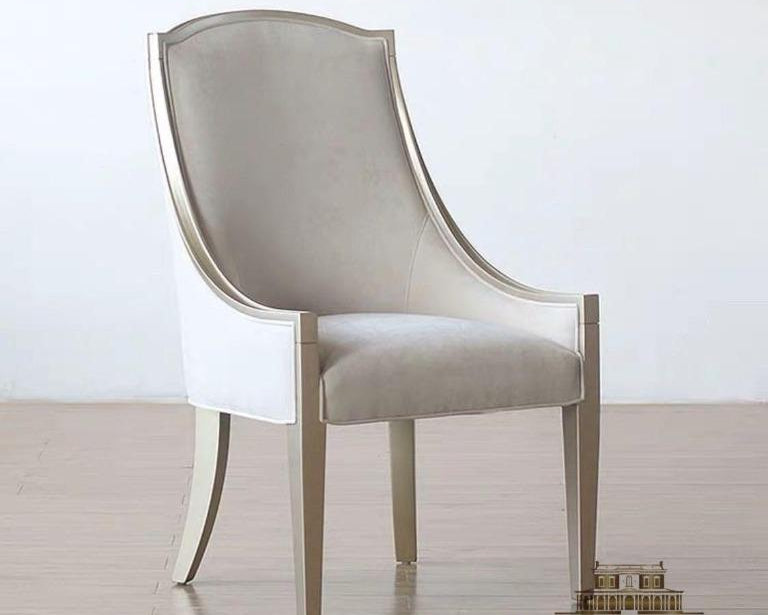 A 'light luxury' style dining chair with a upholstered seat and backrest in white, and a wooden frame with gold elements.