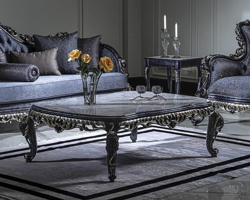 A luxurious French coffee table with carved details, featuring a marble top and a tufted backrest, placed in an elegantly decorated living room setting.