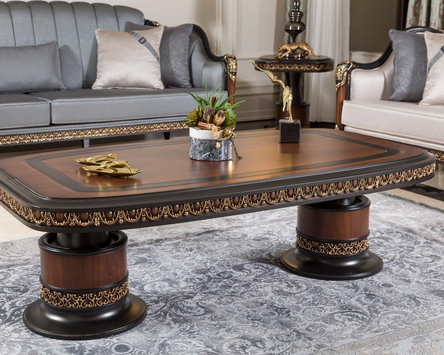 A French coffee table with a rich walnut finish and gold detailing, featuring a round top with a decorative edge and a rectangular base, placed in a room with an elegant interior design.