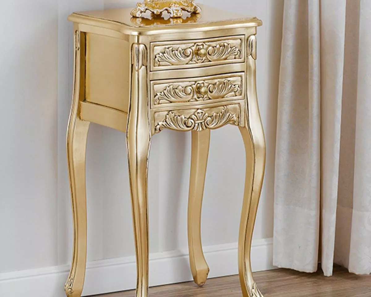 A Victorian style side table with gold color, featuring two drawers and ornate detailing on the legs and top.