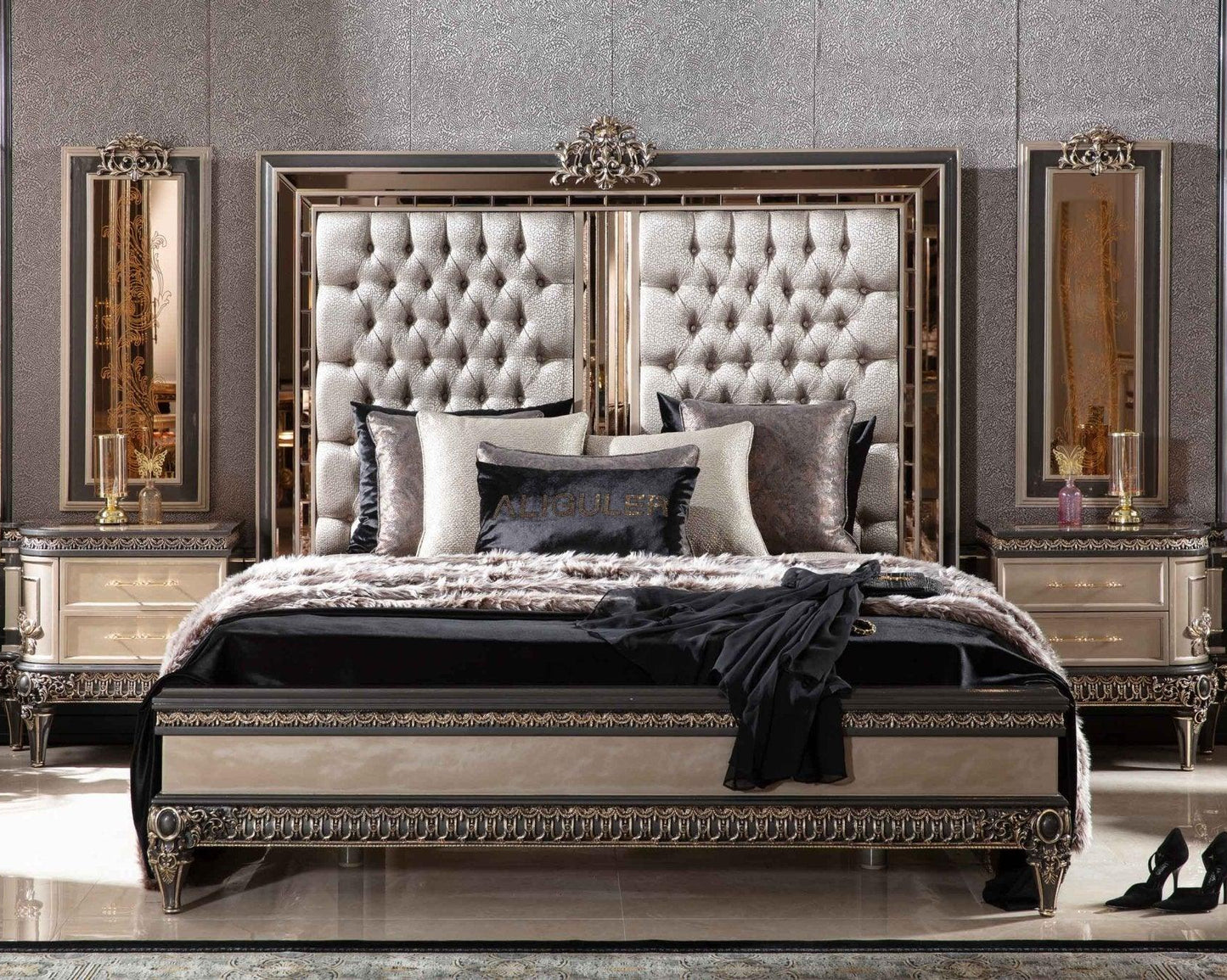 A luxurious bed frame with gold accents, a mirrored frame, and upholstered in a foreign fabric with a solid black headboard and bedding.