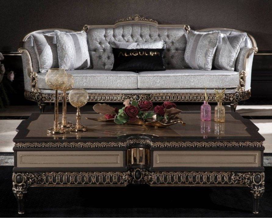 A luxurious French design coffee table made of mahogany, featuring intricate carvings and a polished finish, displayed in a lavishly decorated living room setting.