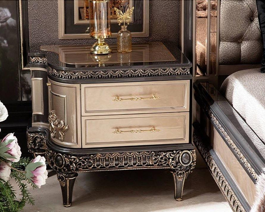 A luxurious French-style nightstand with intricate carved details, featuring a champagne finish and multiple drawers, displayed in a bedroom setting with decorative flowers and a mirrored wall.