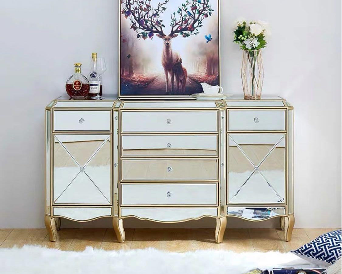 A luxurious mirrored buffet cabinet with silver accents and intricate designs, displayed in a room setting with decorative items on top.