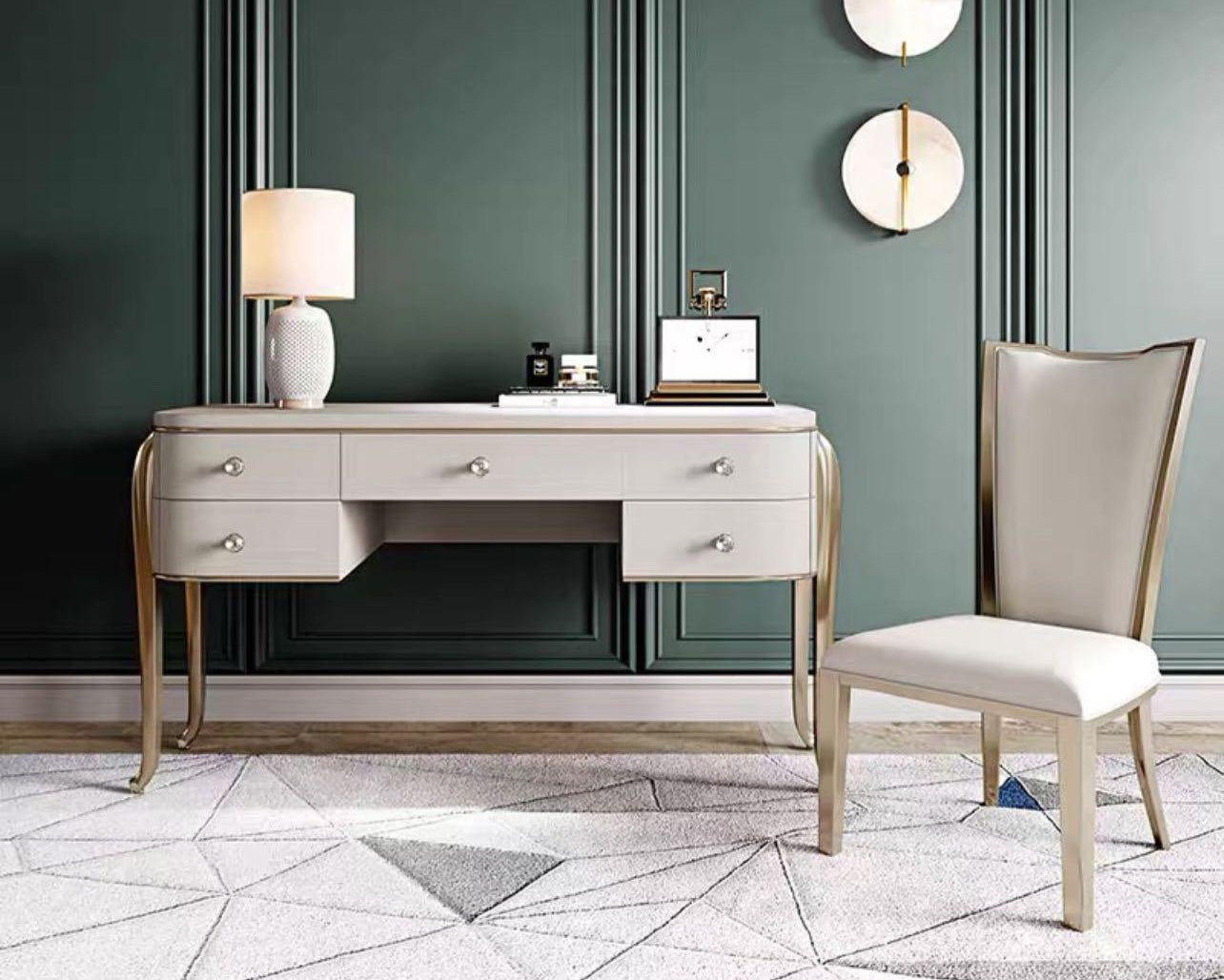 A modern luxury vanity set with a gray desk and gold accents, accompanied by a matching chair, set against a green wall with decorative gold wall sconces.