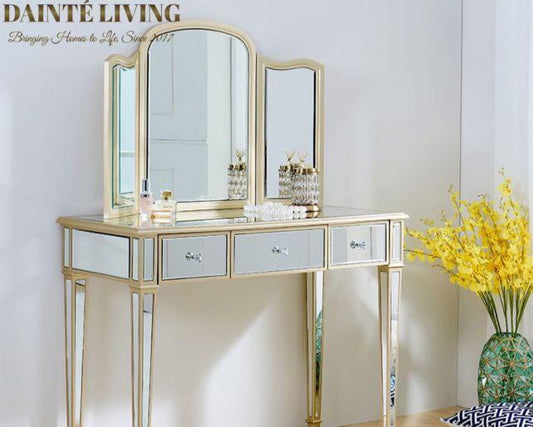 An elegant LOPEZ mirrored vanity set with a gold frame, sterling silver mirror, and mahogany wood legs, displayed in a bright room setting with a stool and multiple drawers.