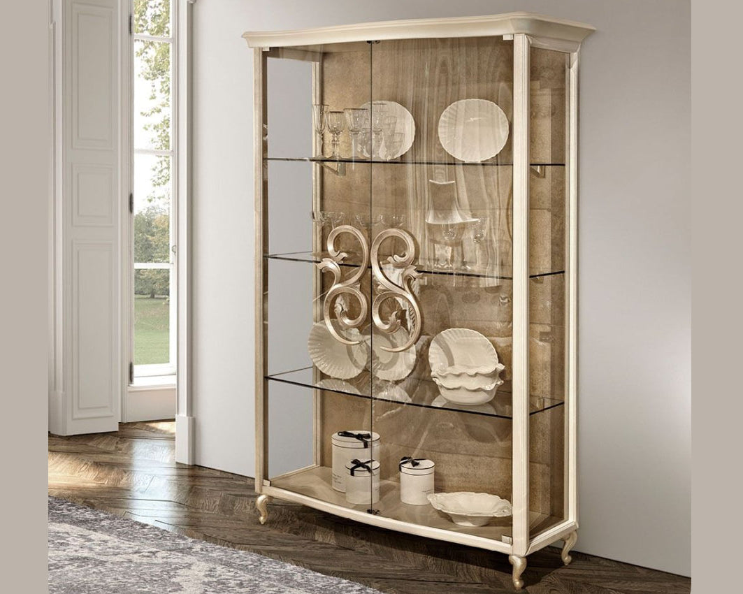 Display cabinet with decorative items in a room with a window and rug.