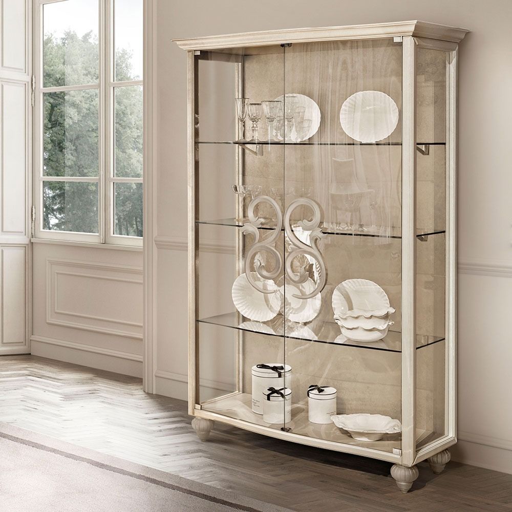 Decorative display cabinet with glass doors in a room with a window and wooden floor.