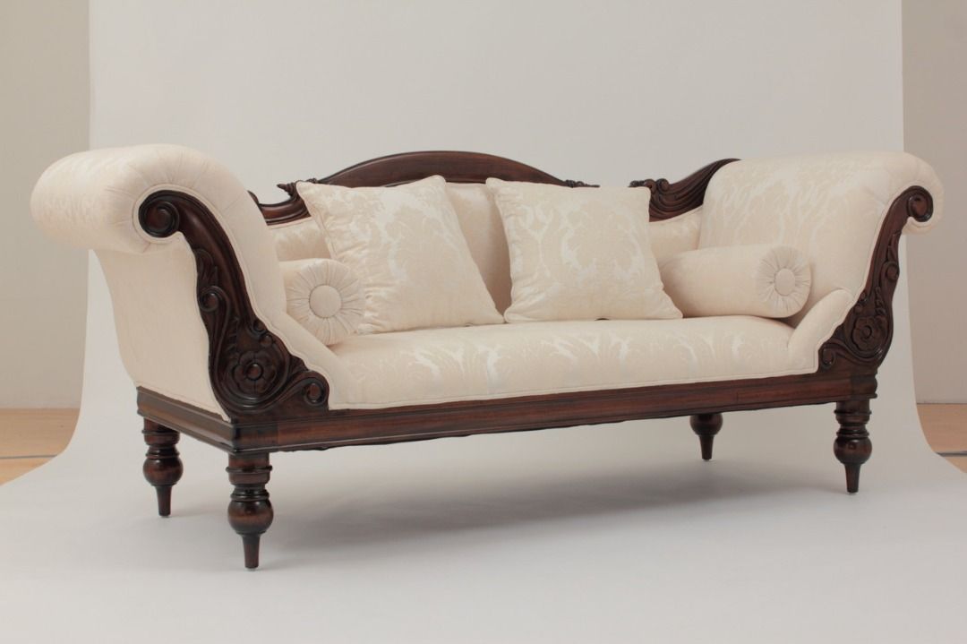 Vintage-style sofa with wooden frame and white cushions on a plain background