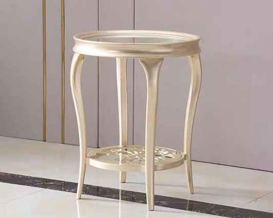 A round, modern Victorian side table with a mahogany wood frame and a glass top, featuring intricate design details on the legs.
