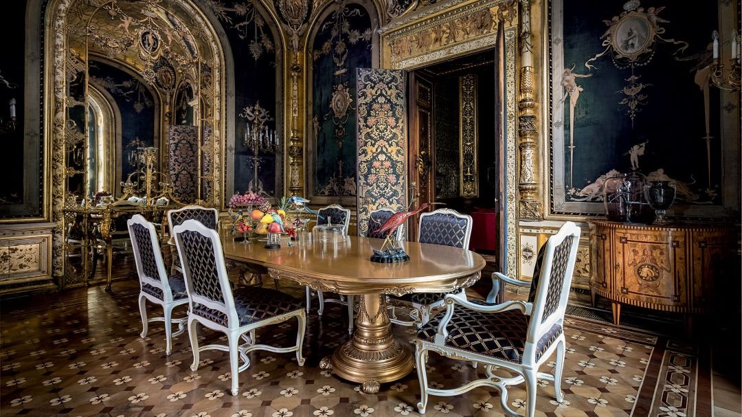 Opulent dining room with ornate decor and a large round table.