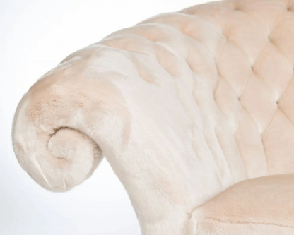 Close-up of a plush, beige armchair with a tufted backrest on a white background