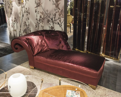 Maroon velvet chaise lounge in a stylish room with decorative elements.