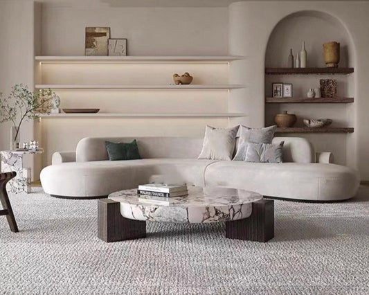Modern living room with a gray sofa, marble coffee table, and shelves with decor.
