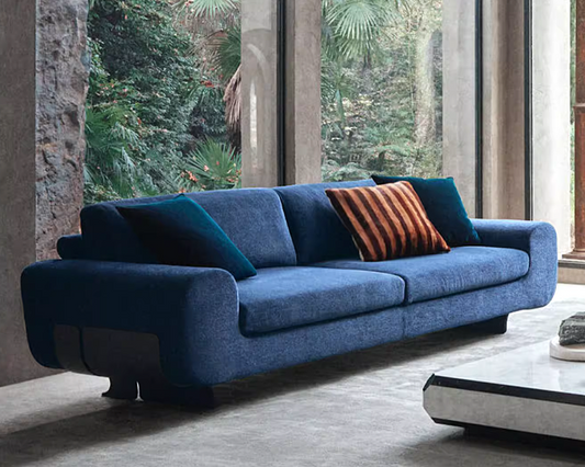 Custom made blue modern stainless steel legs sofa with a striped pillow in a modern living room.