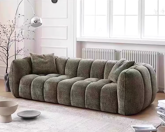 Gray sofa in a living room with a white wall and floor lamp.