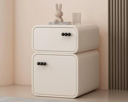 White two-drawer nightstand with black knobs against a beige wall.
