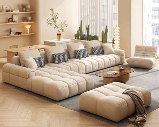 Modern living room with beige sectional sofa, ottoman, and coffee table.