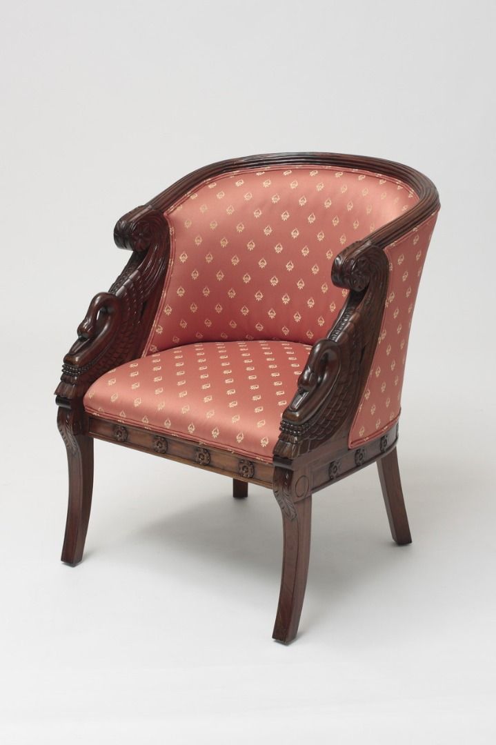 Vintage armchair with pink patterned fabric and wooden frame on a white background