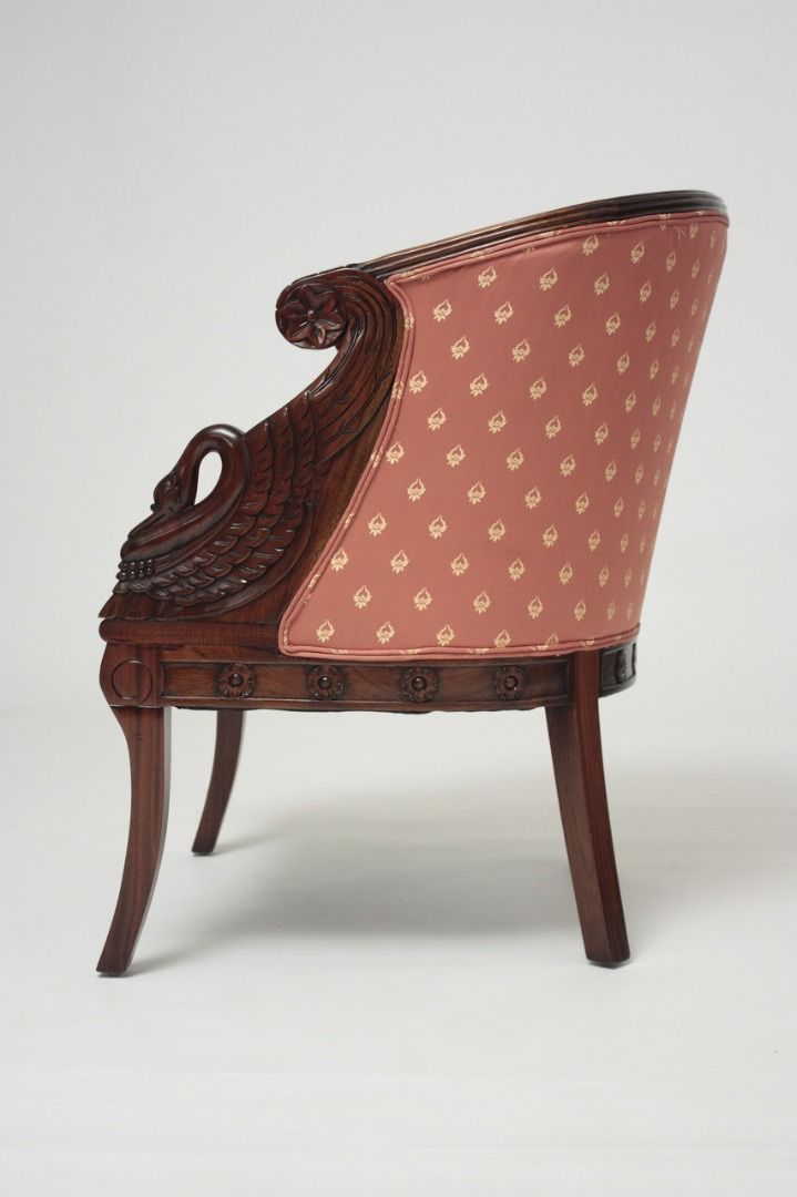 Decorative armchair with wooden frame and patterned pink fabric on a white background