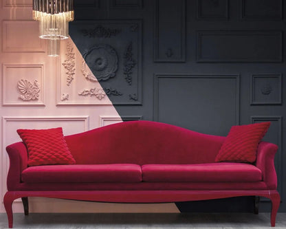 Red sofa with decorative pillows in a room with ornate wall designs and a chandelier.