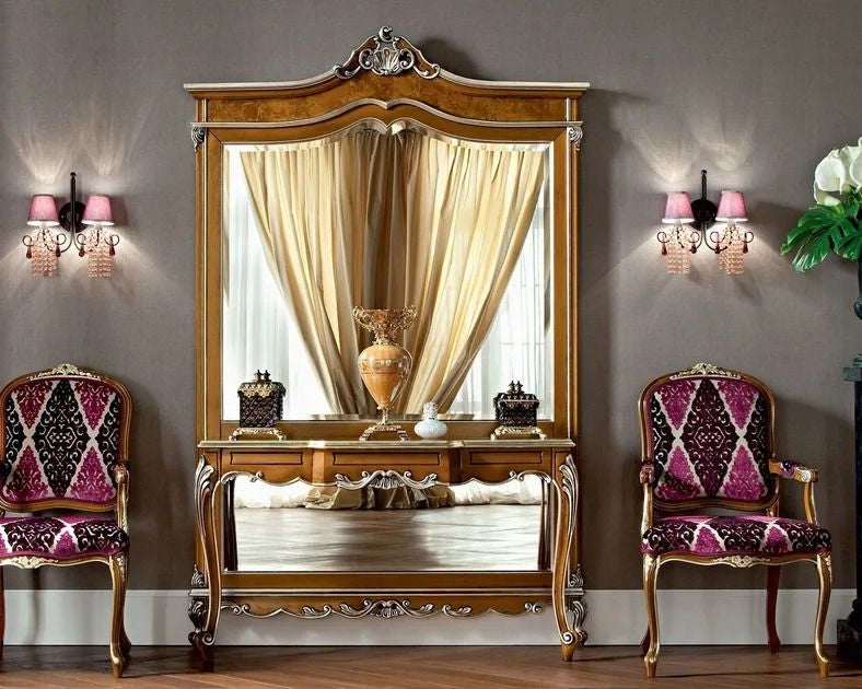 Decorative room with a large ornate mirror, two chairs, and wall sconces.