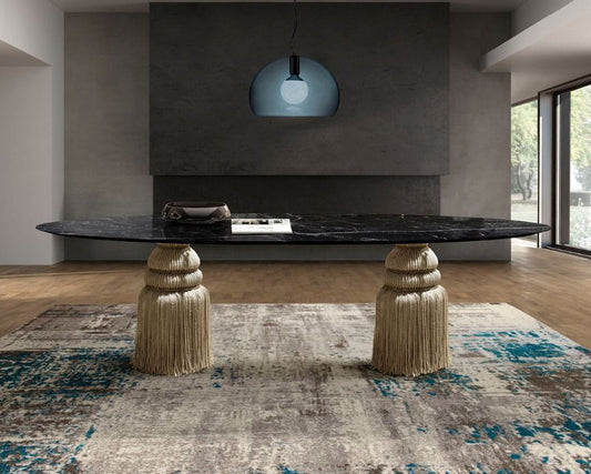 Modern interior with a long dining table and decorative stools on a patterned rug.