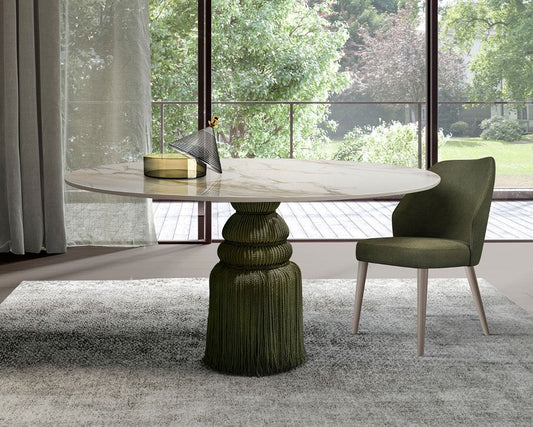 Modern dining table with a textured base and matching chair in a room with large windows.