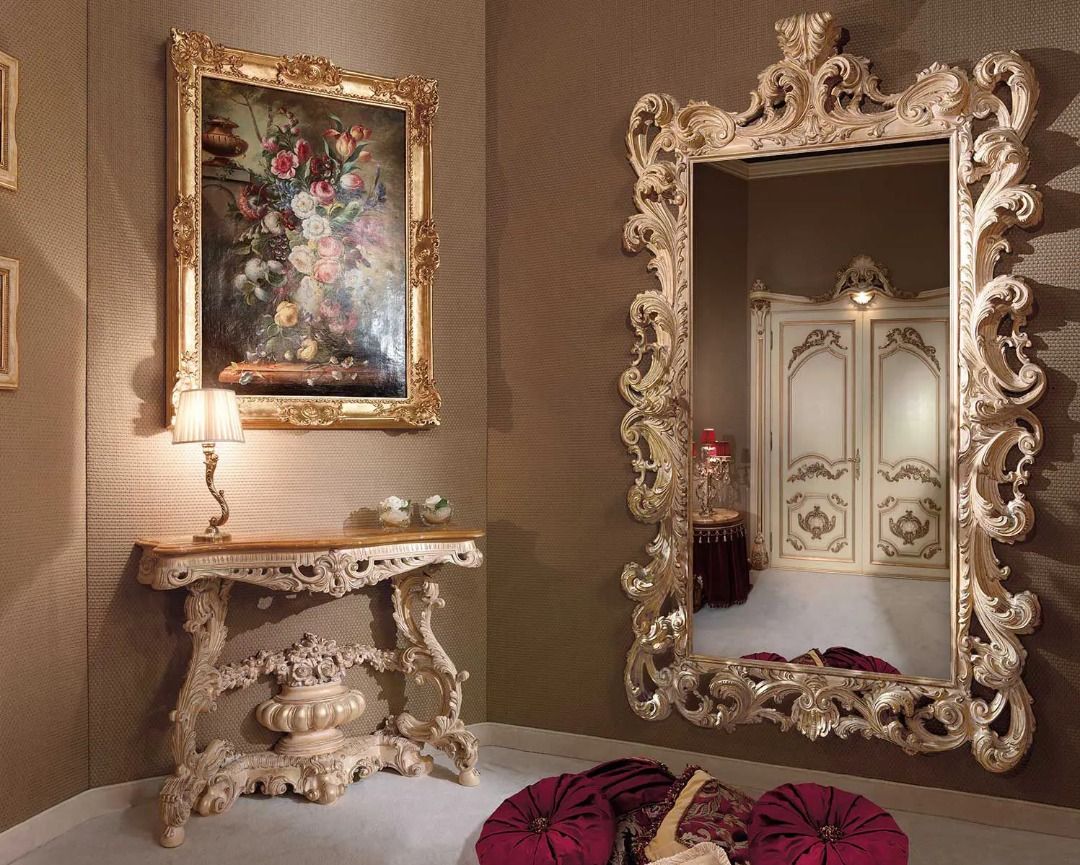 Decorative interior with ornate mirror, table, and floral painting on a brown wall.