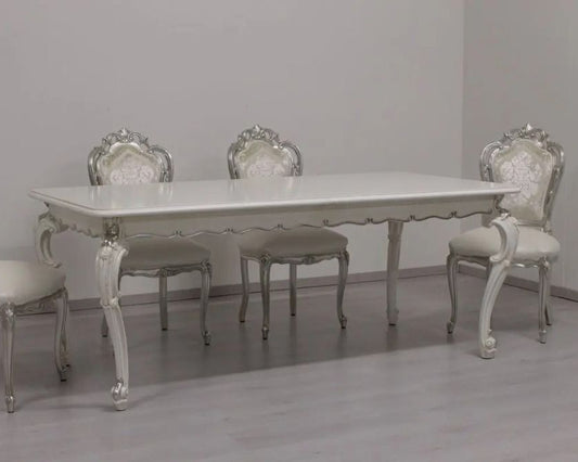 Dining table set with ornate chairs in a room with gray walls and floor.