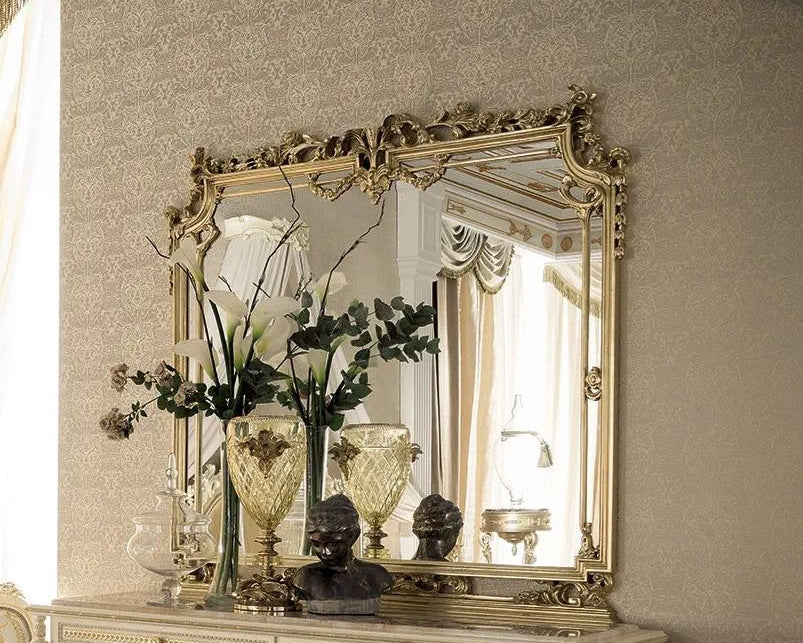 Decorative mirror on a dresser with floral arrangement and decorative items.