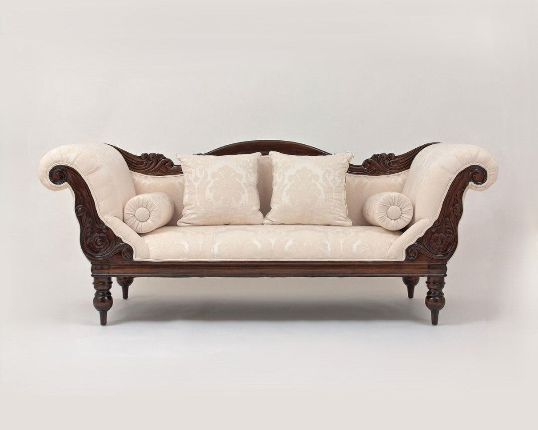Decorative sofa with ornate wooden frame and white cushions on a plain background