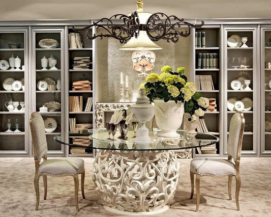 Elegant dining room with a decorative table and chairs, bookshelves, and floral arrangement.