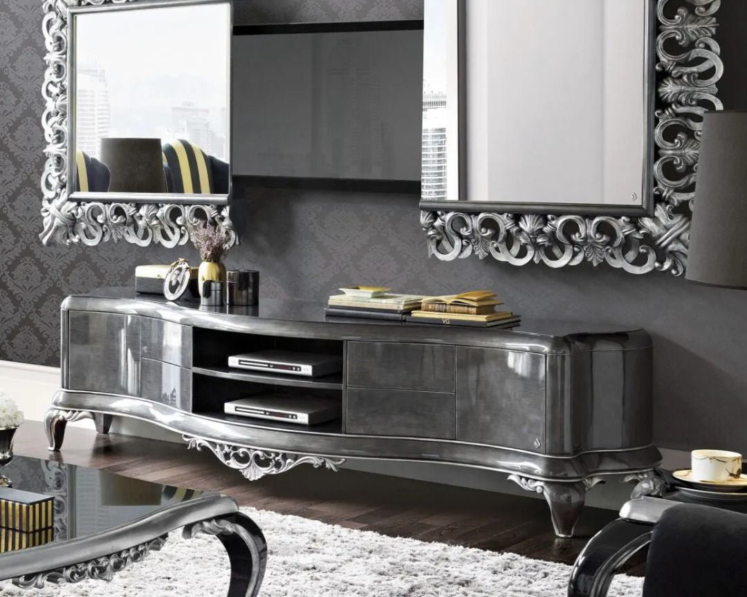 Decorative silver TV stand with ornate mirrors against a gray wall.