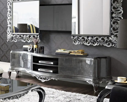 Decorative silver TV stand with ornate mirrors against a gray wall.