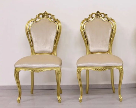 Three ornate gold chairs with beige cushions on a plain background