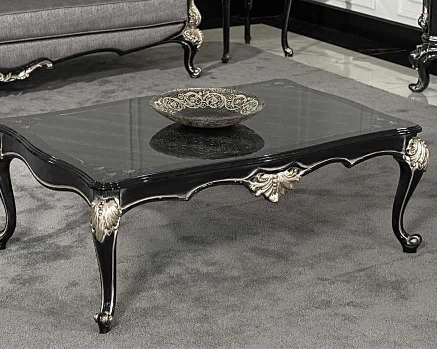 A luxurious baroque style coffee table with intricate carved details and a mirrored top, primarily in black and gold colors.