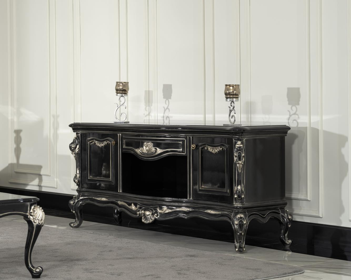 Elegant black baroque-style TV console with intricate carved details and a sleek lacquer finish, featuring shelvings and a frame in a luxurious living room setting.