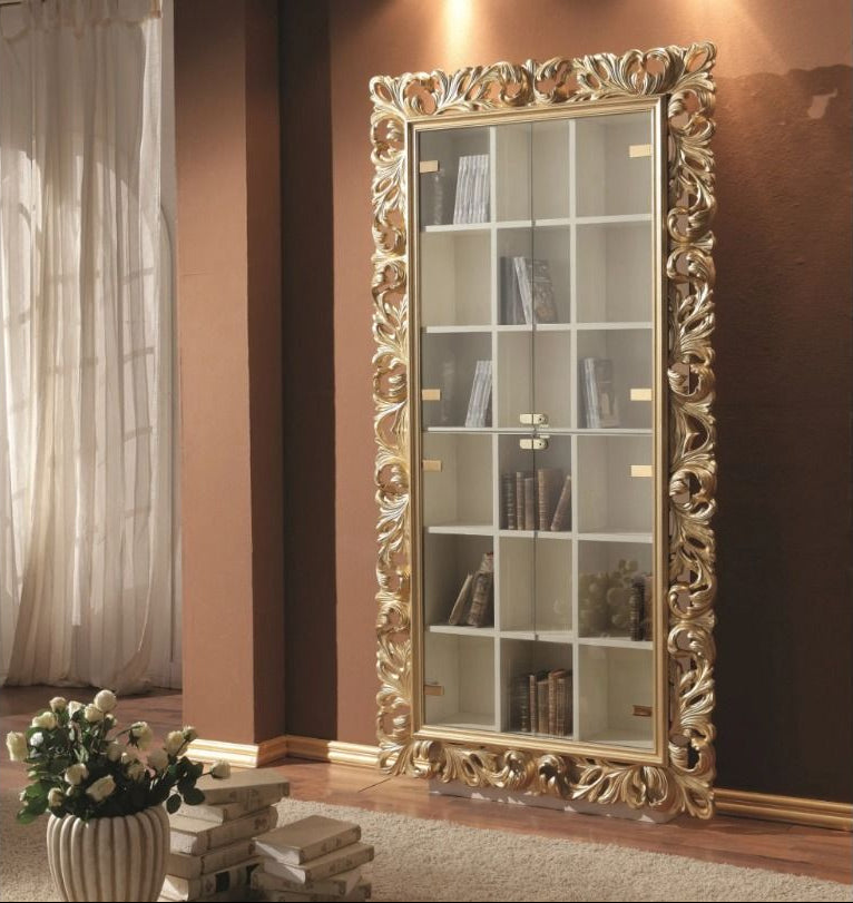 Decorative bookshelf with ornate gold frame in a room with brown walls and a window.