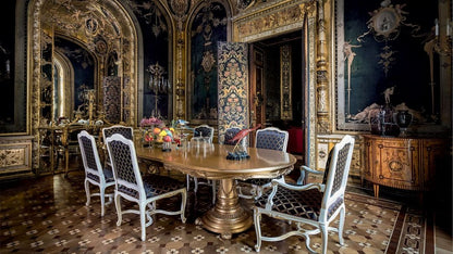 Opulent dining room with ornate decor and a large round table.