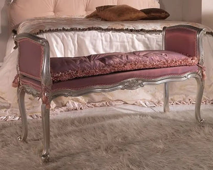 Decorative bench with pink cushion and silver frame in front of a bed.