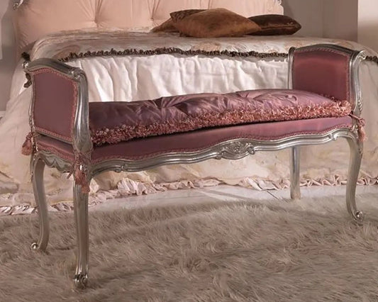 Decorative bench with pink cushion and silver frame in front of a bed.