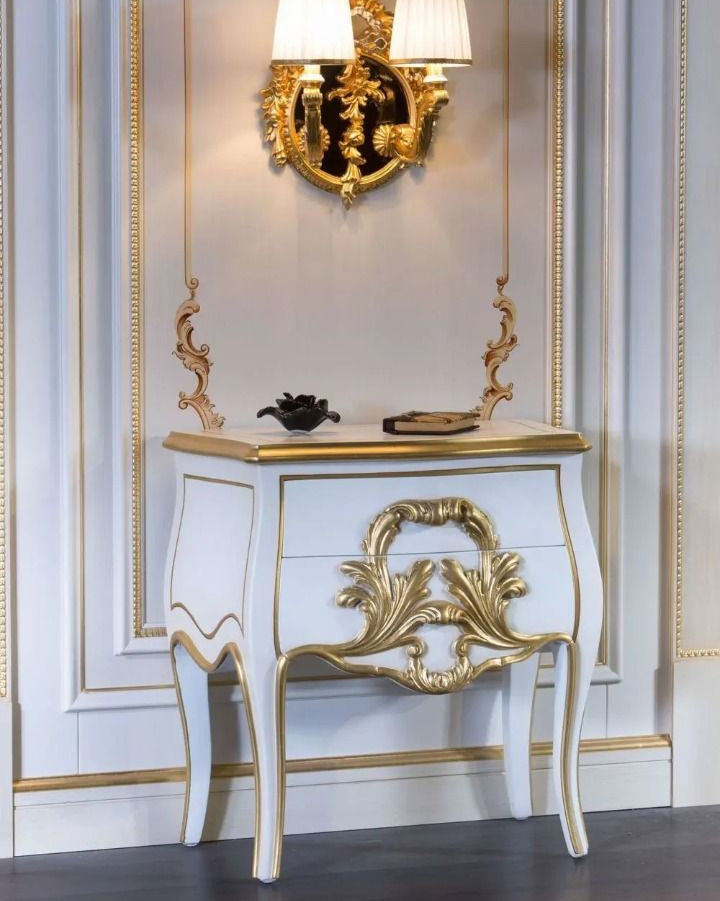Decorative console table with gold accents against a wall with decorative molding.