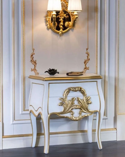 Decorative console table with gold accents against a wall with decorative molding.